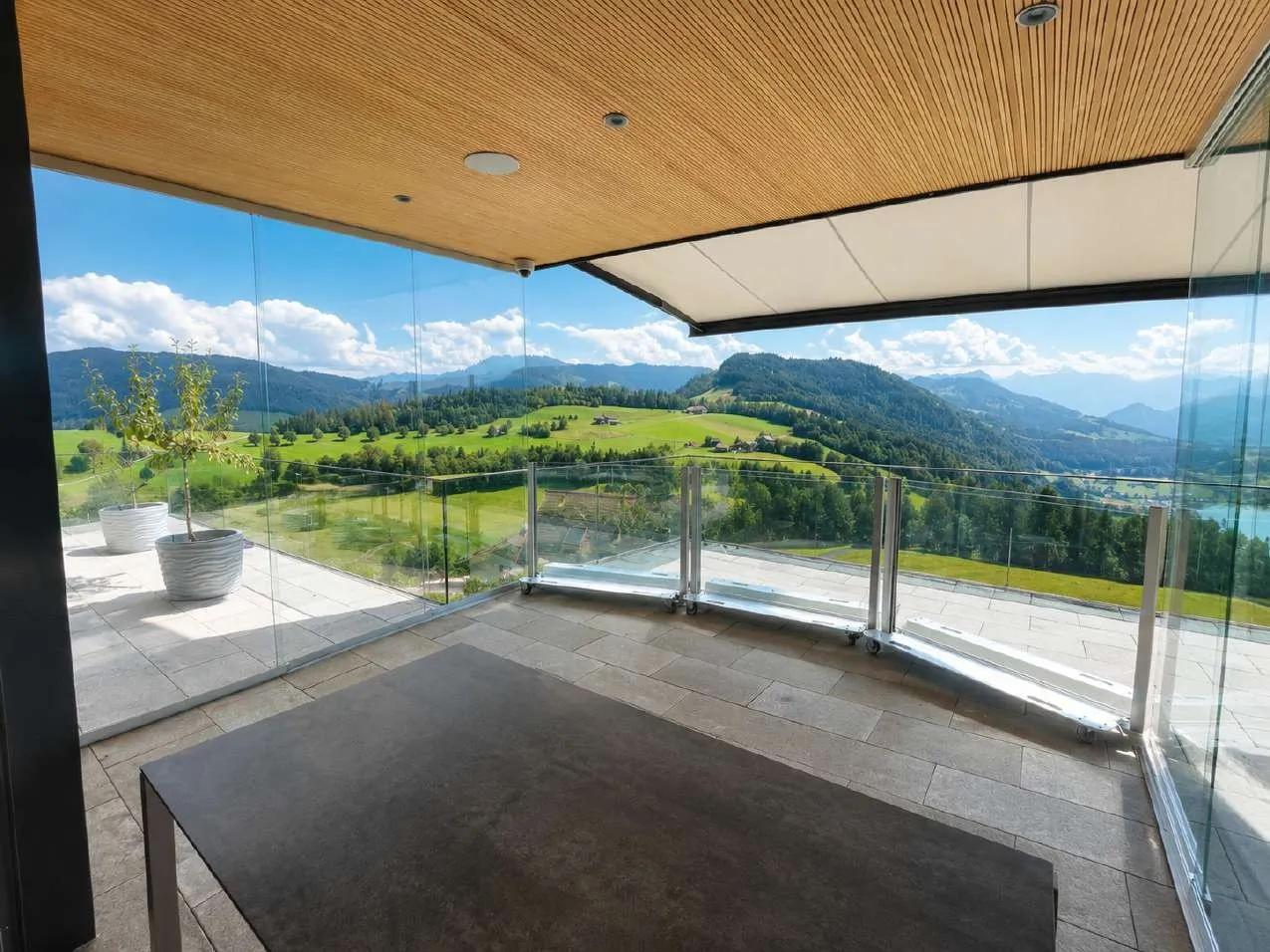 A lowered SlideGlass guardrail around a covered terrace, looking out over green hills.
